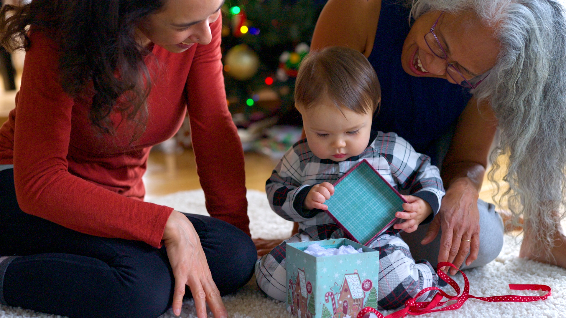mom, grandma, and baby opening gifts