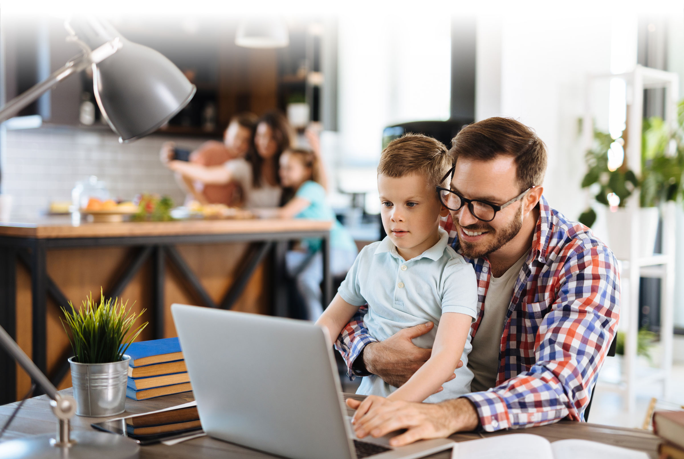 Dad with son on computer with family behind them